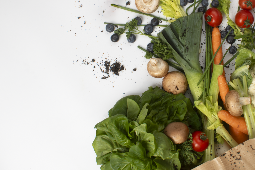 Photograph shows vegetables spilling out of a shopping bag, surrounded by pieces of peat - which is what has been used to grow them